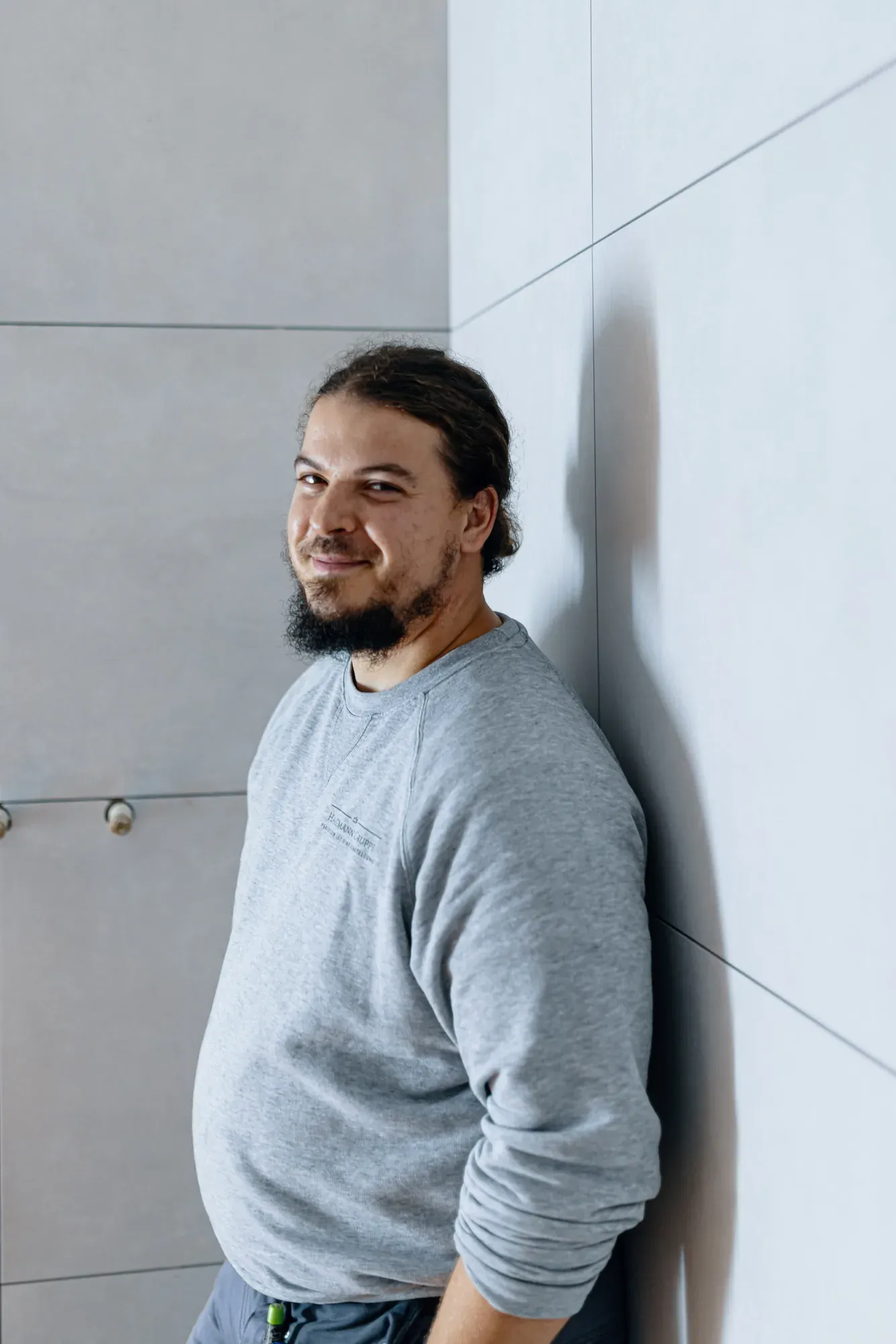 Patrick Hartmann auf einer Baustelle vor einer frisch gefliesten Wand