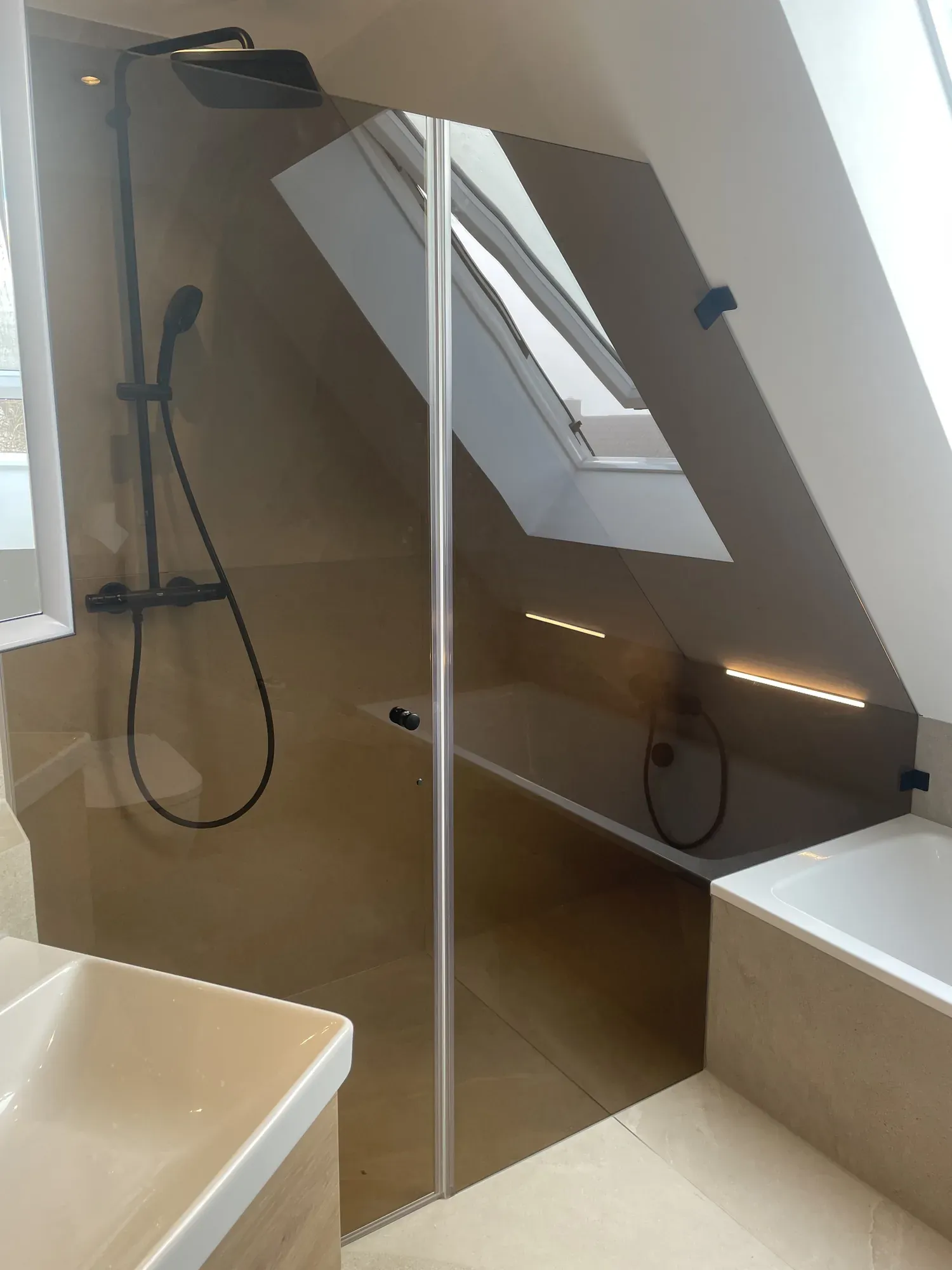 Glasdusche neben der Badewanne unter dem Dachfenster