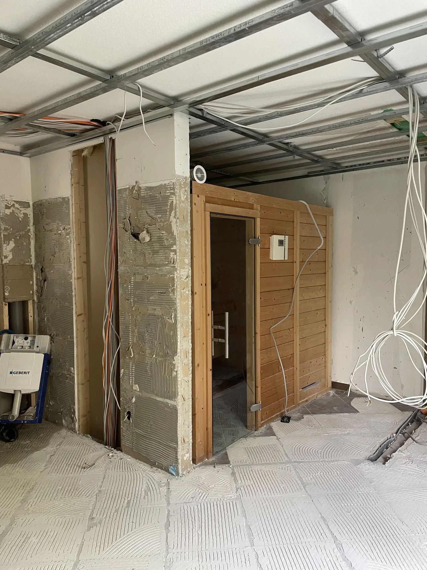 Entkerntes Bad mit abgeschlagenem Putz, Metallständern an der Decke und alter Sauna
